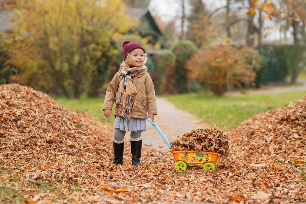 girl playing in a pile of leaves